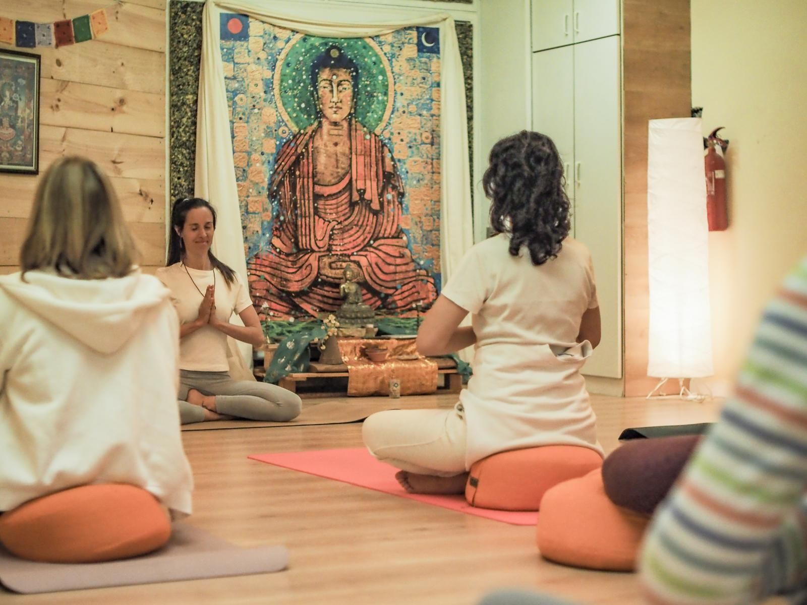 Grupo en meditación con las manos en namasté durante una clase de Kundalini Yoga