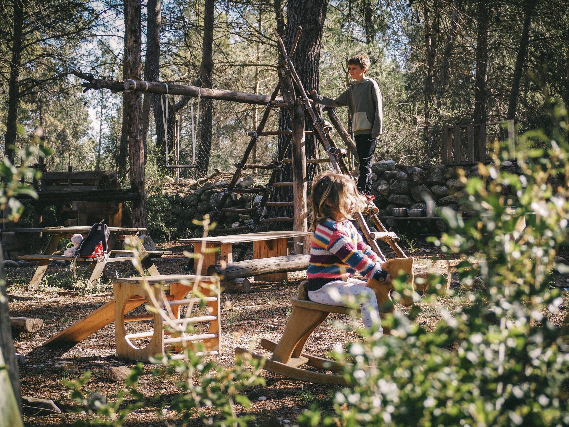 Dos niños jugando en la zona de juego de madera junto a la casa del retiro
